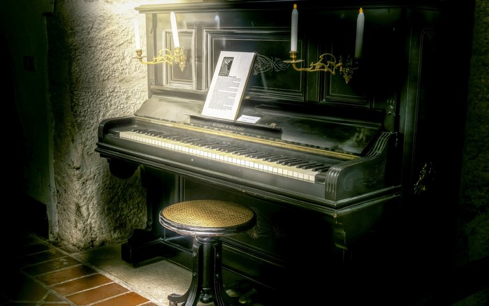 Antique upright piano with stool and sheet music