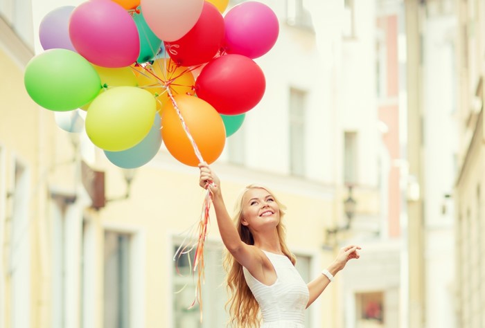 Blonde girl holding colorful balloons