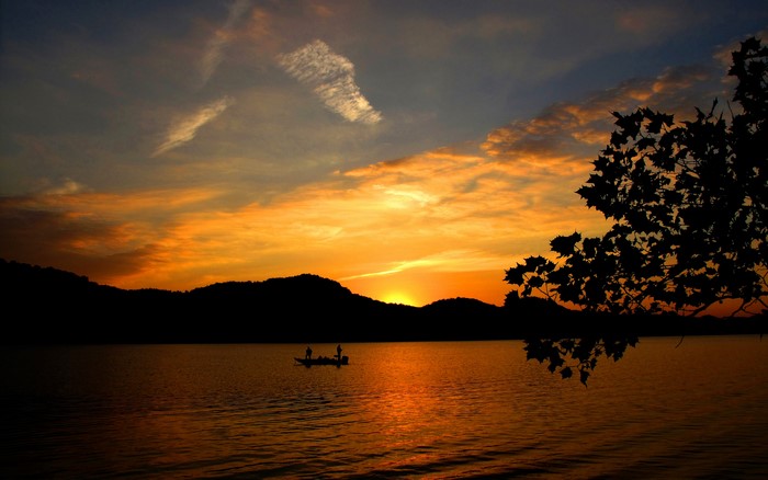 Sunset over a lake with fishermen in a boat