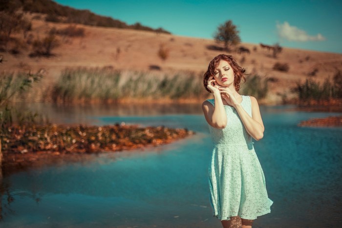 Woman in a light blue dress by a pond