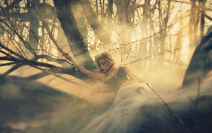 Blonde woman in a forest with fog