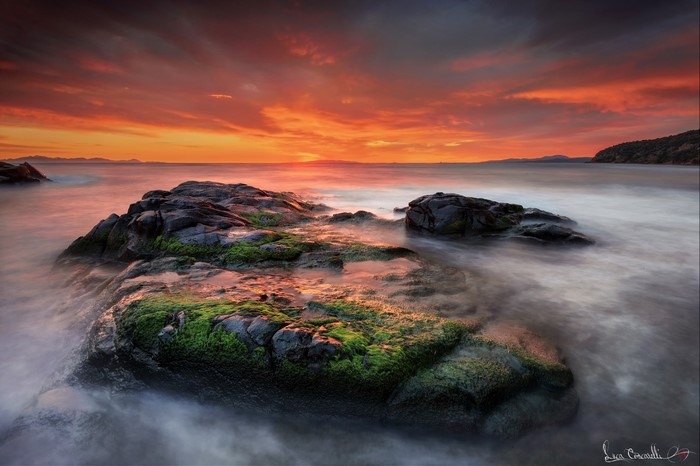 Sunset over the sea with mossy rocks