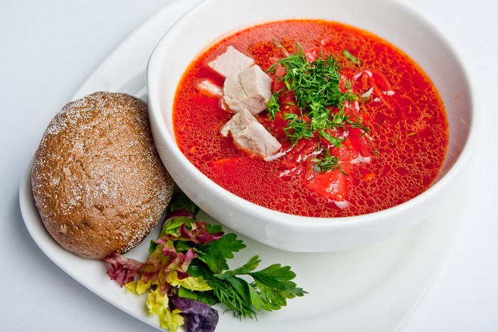 Borscht soup with meat, bread, and salad on a plate
