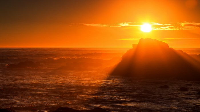 Golden Sunset Over Rocky Sea with Sun Rays