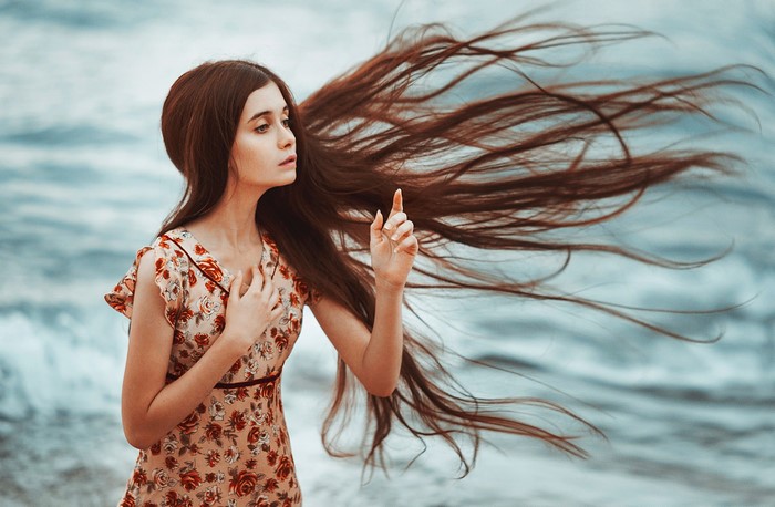 Woman with long brown hair by the sea