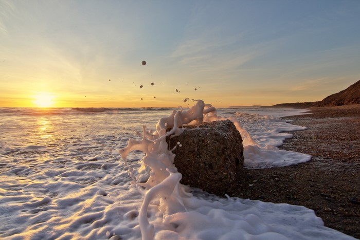 Waves crashing on a rock at sunset