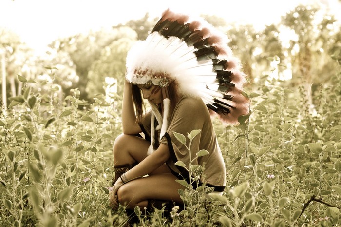 Woman wearing a Native American headdress in a field