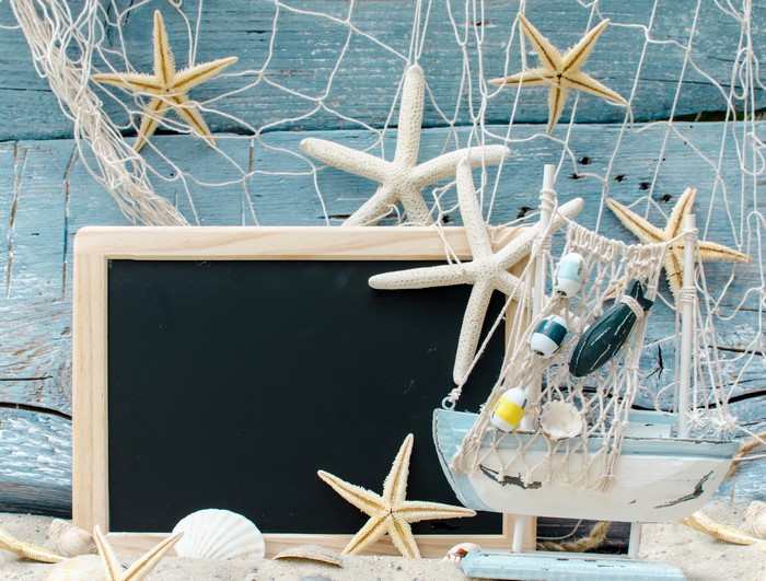 Beach scene with starfish, seashells, and a model boat