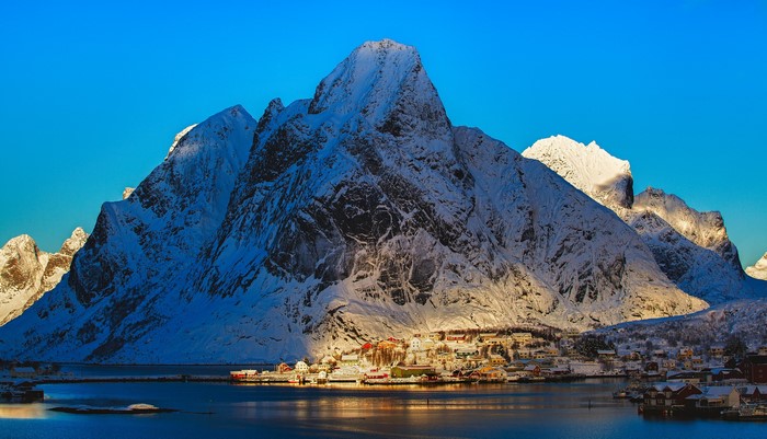 Snow-covered mountains and a village by the water