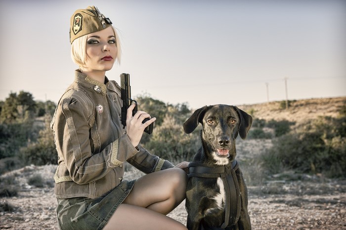 Woman in military uniform with a dog and a pistol