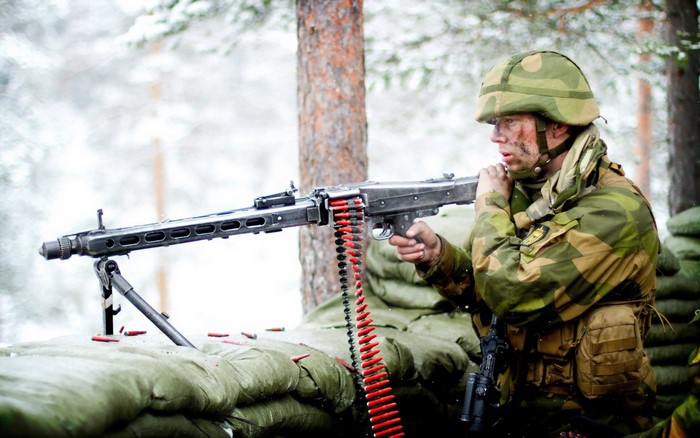 Soldier firing a machine gun in a snowy forest