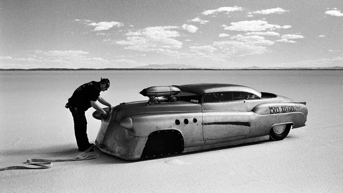 Man working on a custom car on a salt flat