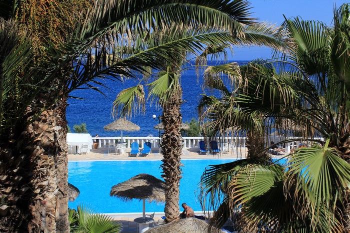 Resort pool with palm trees in Kamari, Greece