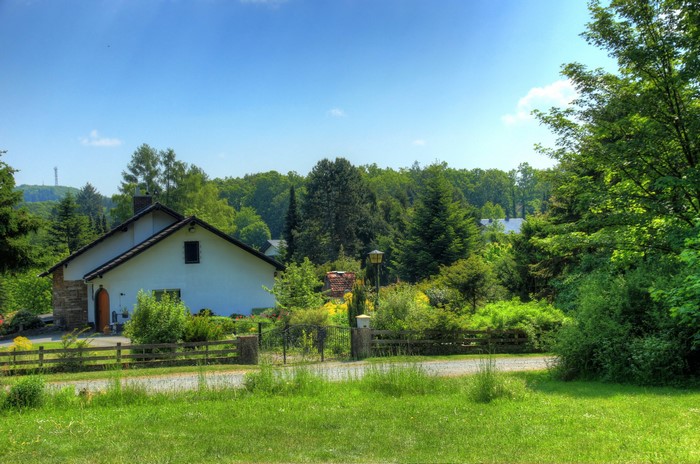 House in a green landscape with trees and blue sky
