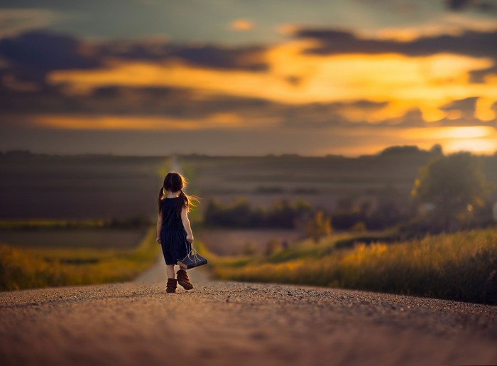 Girl walking on a road at sunset
