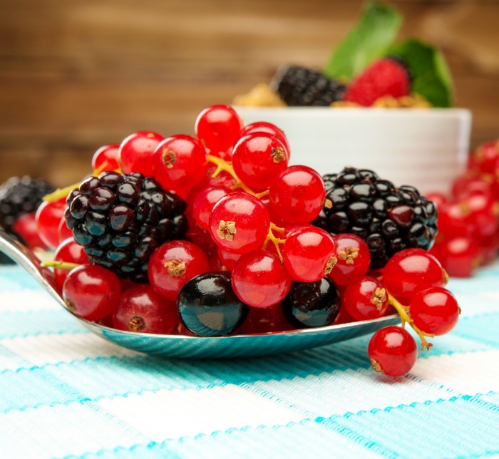 Red currants and blackberries on a spoon