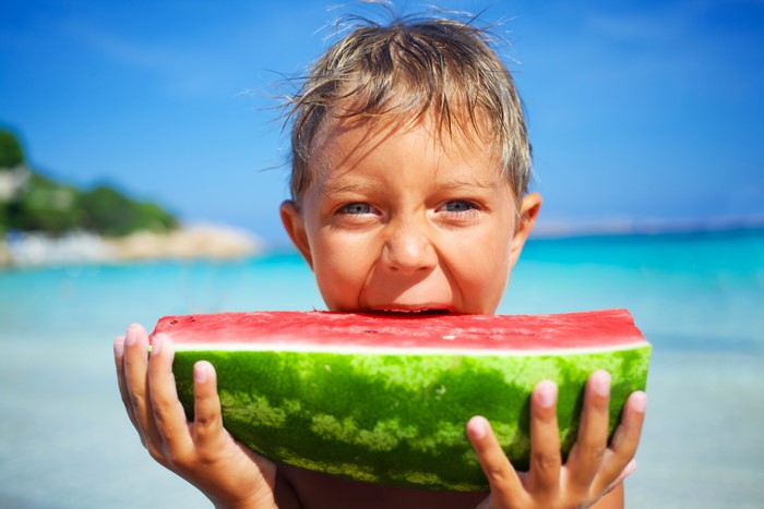 Boy eating watermelon on beach