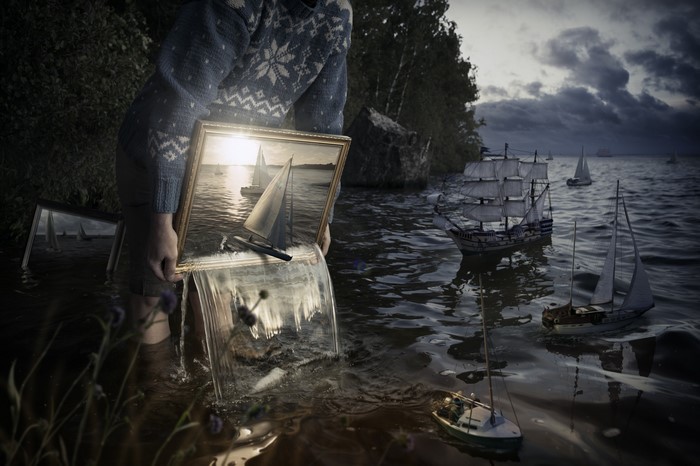 Person holding a painting of sailboats with water pouring out