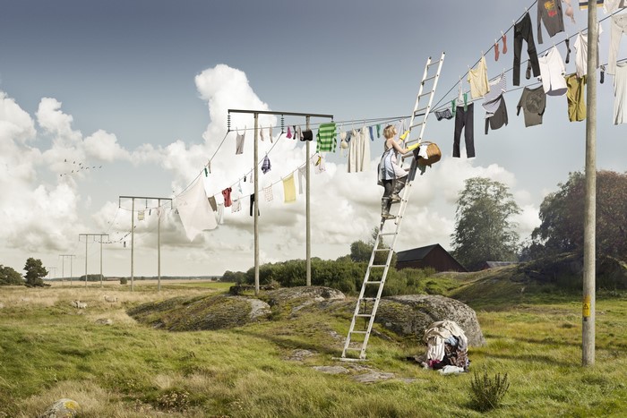 Woman hanging laundry on a clothesline with a ladder