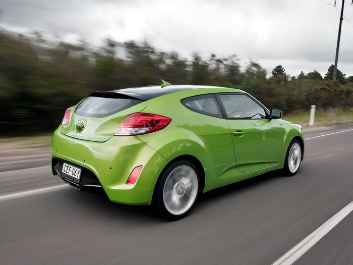 Green Hyundai Veloster driving on a road