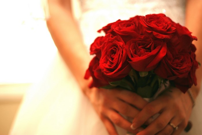 Bride holding a bouquet of red roses
