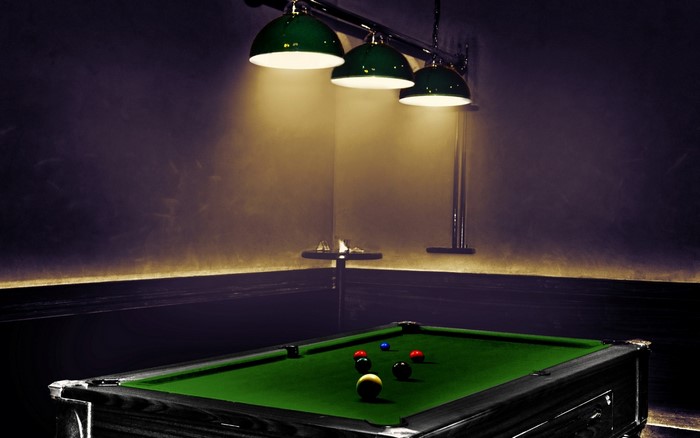 Billiard table with balls under green lamps