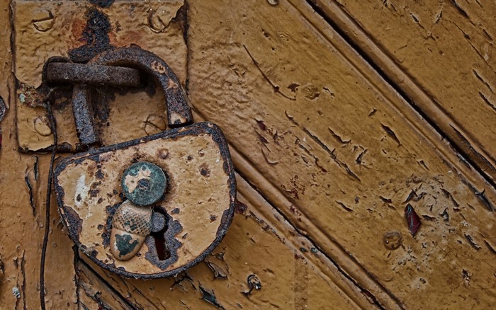 Old rusty padlock on a weathered wooden door