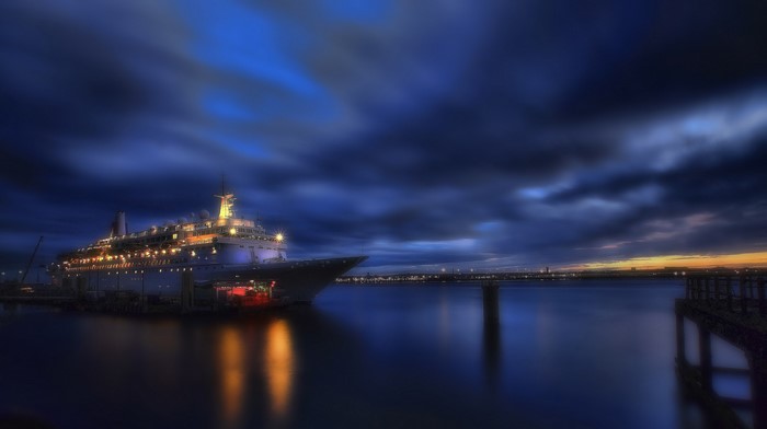 Cruise liner docked at night with dramatic clouds