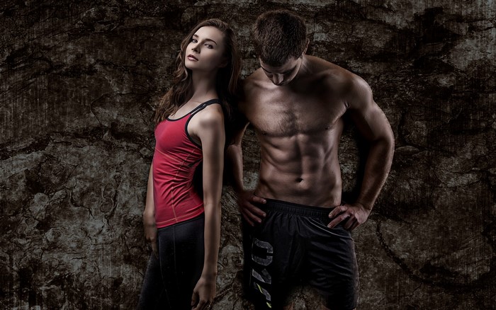 Fit man and woman posing against textured wall