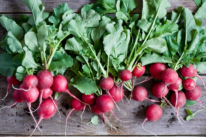 Fresh Radishes with Green Foliage on Wooden Surface