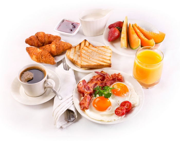 Breakfast with coffee, croissants, bacon, eggs, and fruit