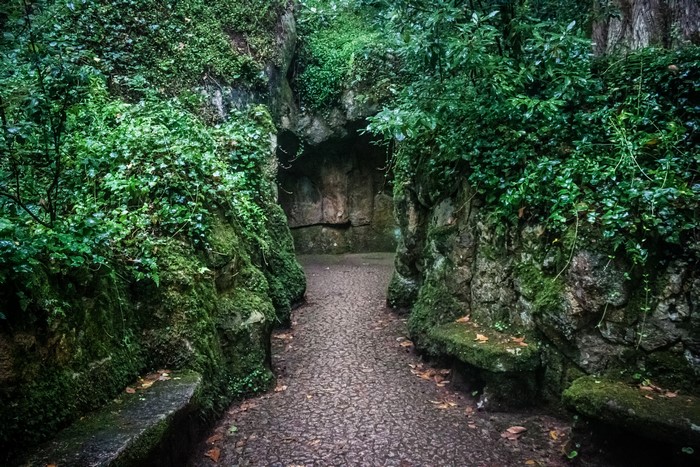 Mossy stone benches and path leading to a cave entrance
