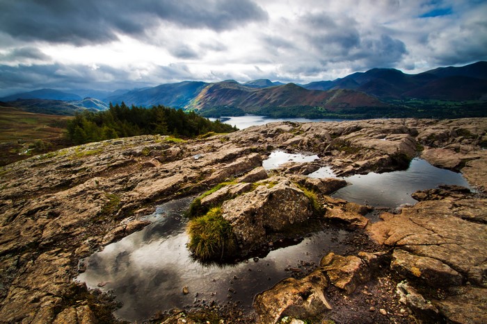 Rocky landscape with puddles overlooking mountains and lake