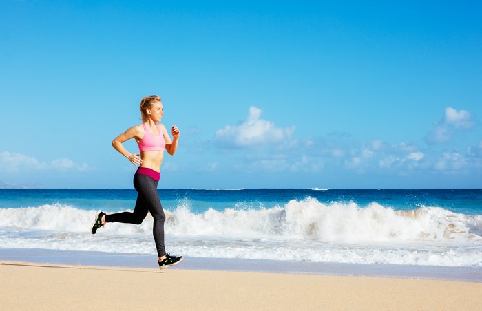 Woman running on a beach with waves and blue sky
