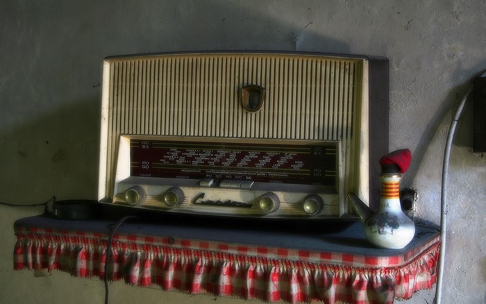 Vintage radio receiver on a shelf with a decorative pitcher