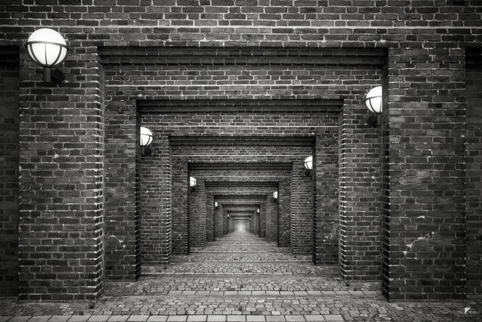 Brick hallway with repeating arches and lights