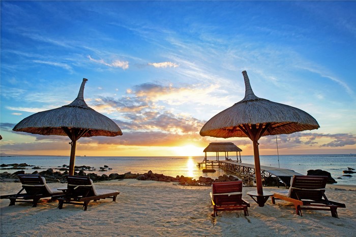 Beach with lounge chairs and umbrellas at sunset