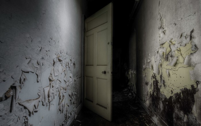 Abandoned hallway with peeling paint and open door