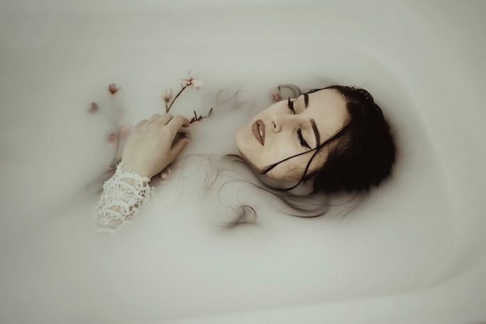 Woman lying in a milk bath with flowers