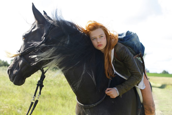 Redhead girl on a black horse