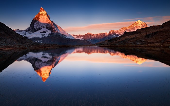 Matterhorn mountain reflected in a calm lake at sunrise