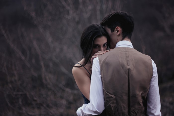 Couple embracing, woman glancing over shoulder