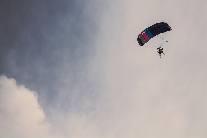 Skydiver with colorful parachute against cloudy sky