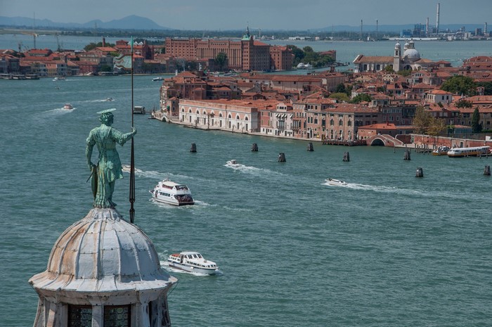Statue overlooking Venice canal with boats
