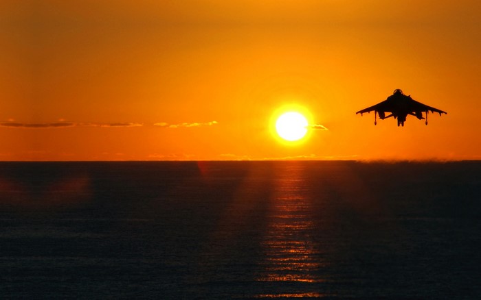 Airplane flying over the sea at sunset