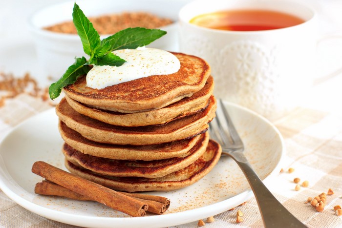 Stack of pancakes with cream and mint, cinnamon sticks, and tea