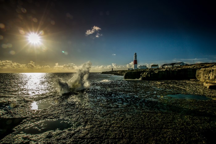Portland Bill Lighthouse on a rocky coast with waves crashing