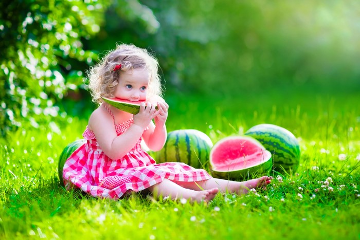 Little girl eating watermelon in grass