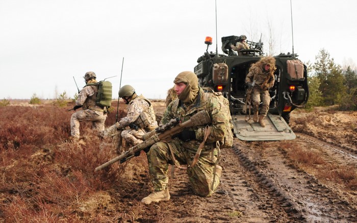 Soldiers with rifles near an armored vehicle