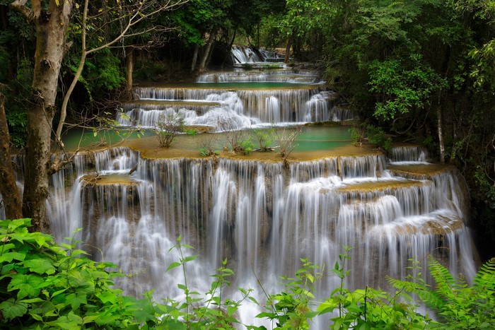Tiered waterfalls cascading through a lush green forest